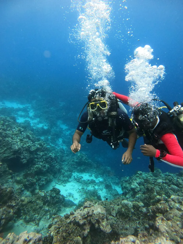 A scuba diver with an instructor over coral in Lakshadweep